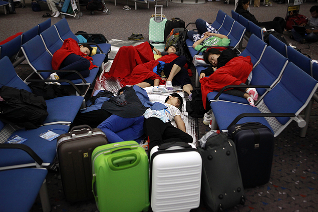ORG XMIT: XHG111 Passengers sleep near their luggage after Typhoon Vicente stranded flights out of the airport in Hong Kong on Tuesday morning, July 24, 2012. Planes grounded at the financial capital's international airport were buffeted by the high winds early Tuesday. Passengers were told the conditions were expected to last several hours. (AP Photo/ Ng Han Guan)